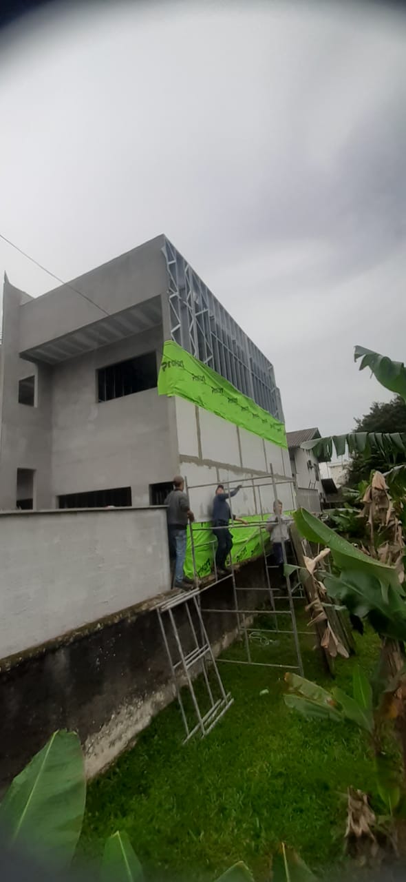 Equipe instalando placas de drywall na fachada de obra em andamento